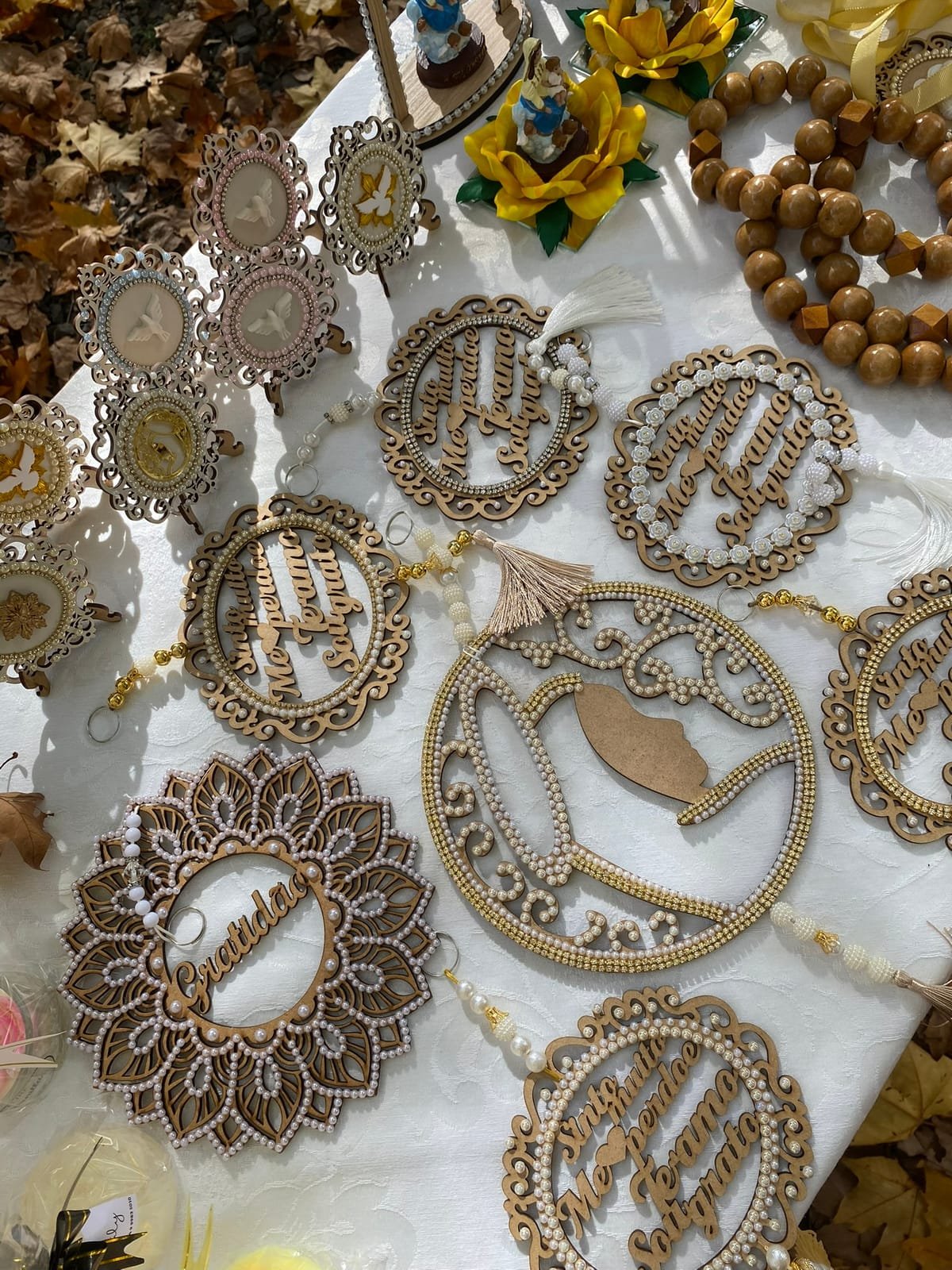Mandalas de madeira recortada, terços e enfeites sobre a toalha branca