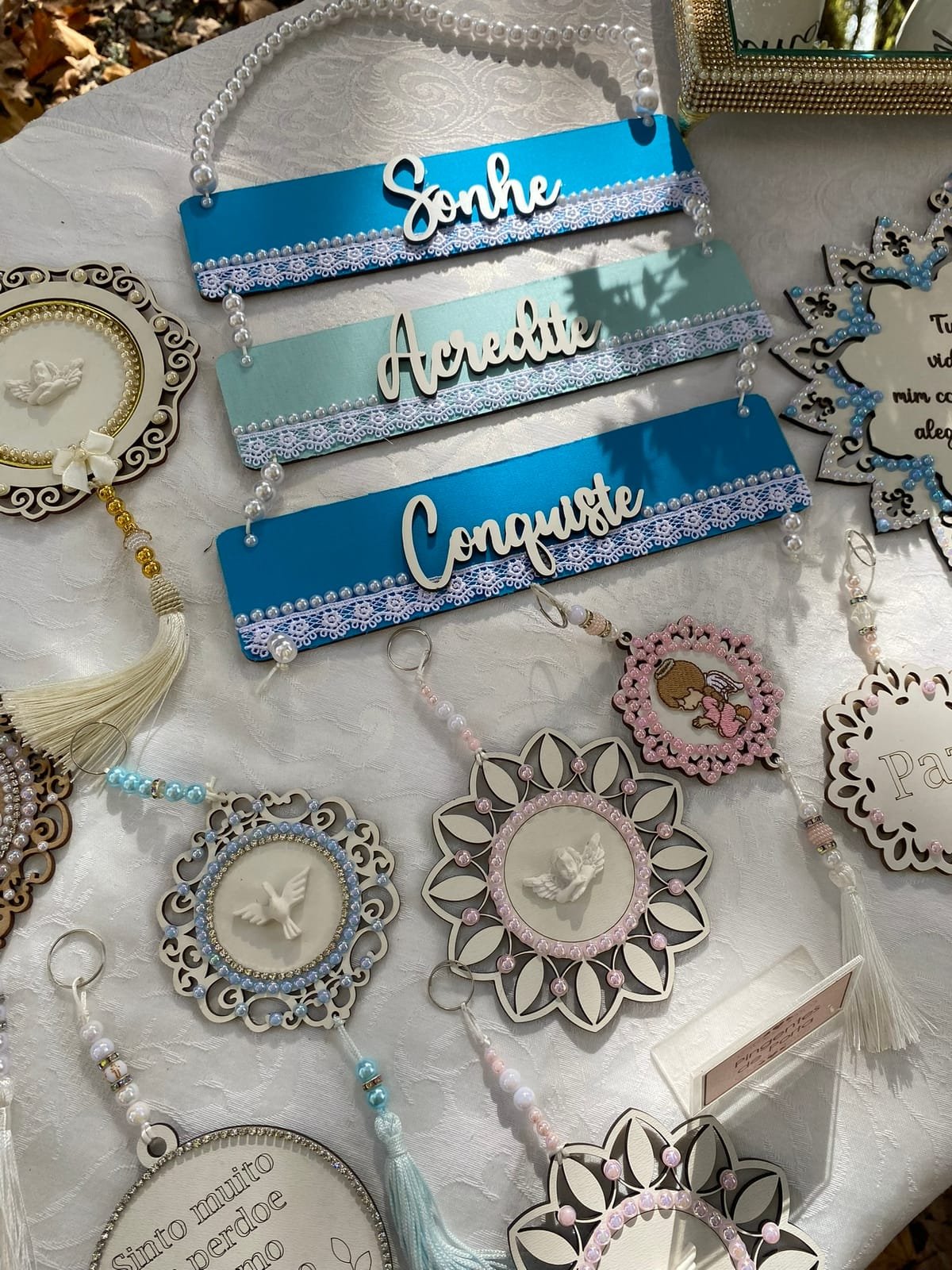 Placas azuis penduradas com as palavras sonhe, acredite e conquiste, entre mandalas artesanais