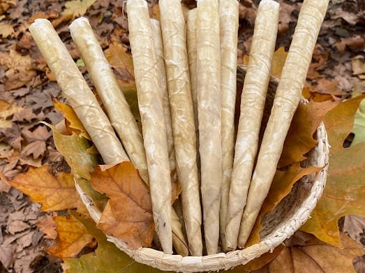 Velas de cone feitas de tecido encerado, num cesto sobre as folhas secas