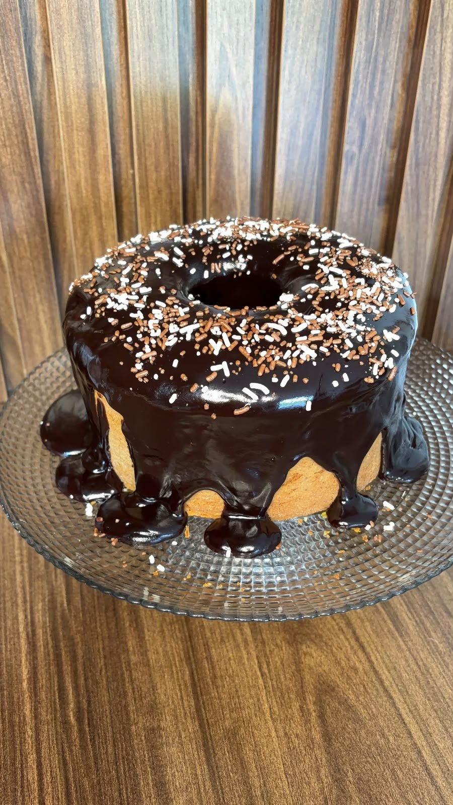 Bolo de laranja caseiro com cobertura de chocolate escorrendo e coco ralado por cima