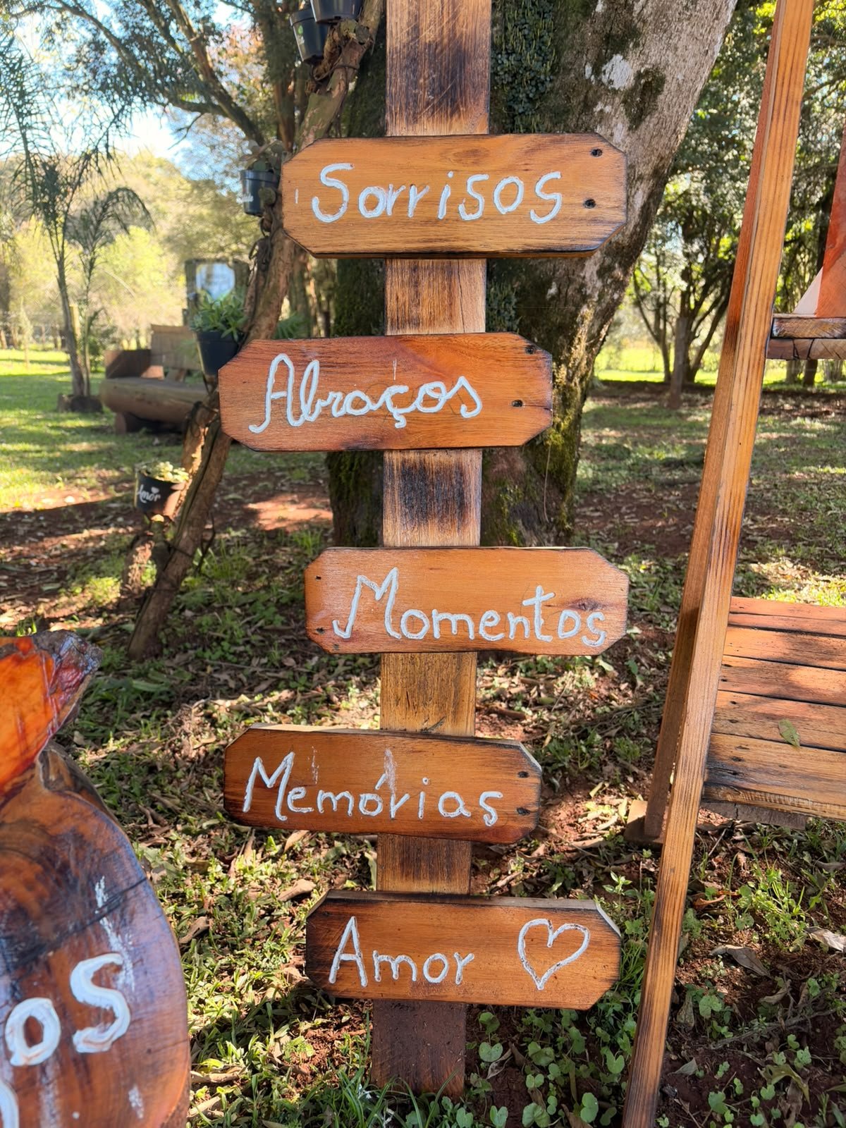 Poste de madeira com placas escritas sorrisos, abraços, momentos, memórias e amor