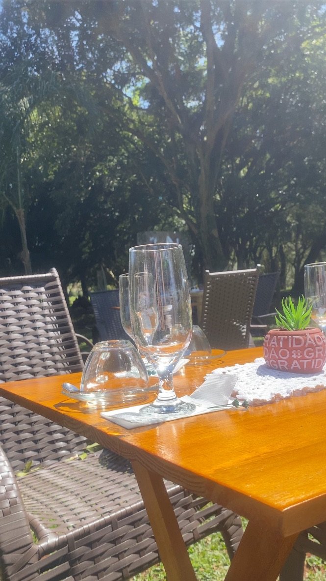 Mesa posta sob as árvores, com taças e um vaso escrito gratidão