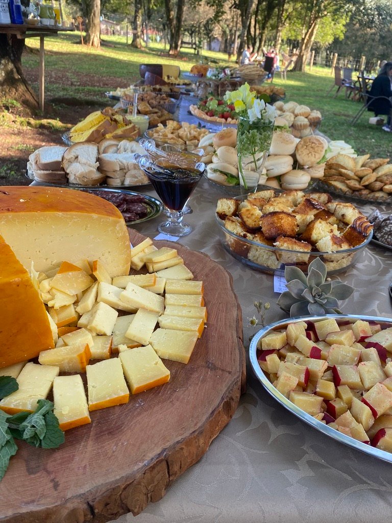 Mesa do café colonial com tábua de queijos, pães, cucas e doces